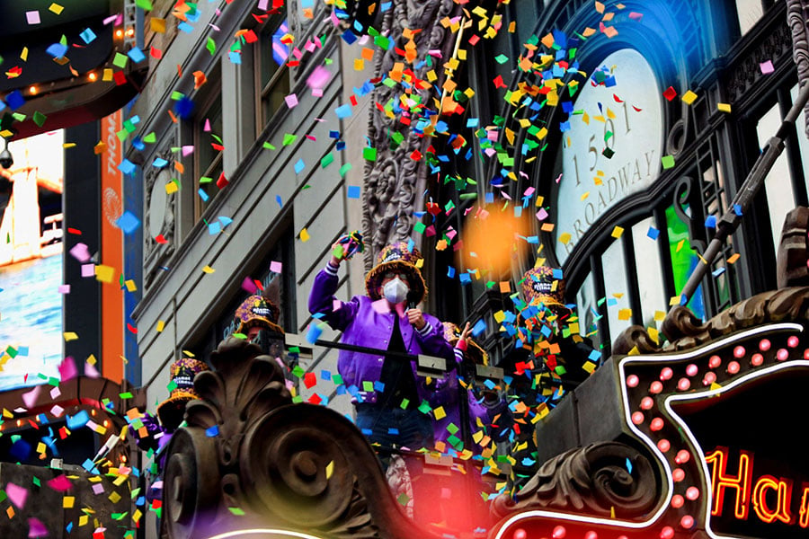 New Years festivities, confetti and man in purple outfit amidst parade